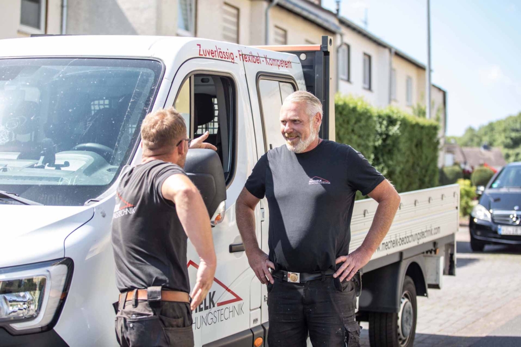 Zwei Dachdecker im Gespräch neben Transporter